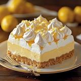 A plated slice of lemon cheesecake with meringue topping.