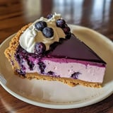 A piece of creamy cheesecake with blueberry mousse on top.